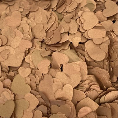 A dense pile of small heart-shaped paper confetti in warm metallic brown shades.