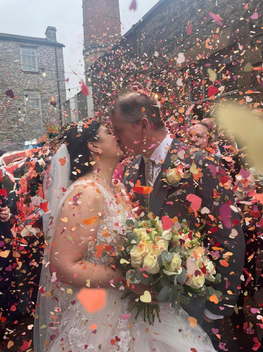 Newlyweds kissing under a shower of heart confetti